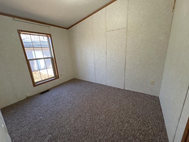 carpeted spare room featuring visible vents and crown molding