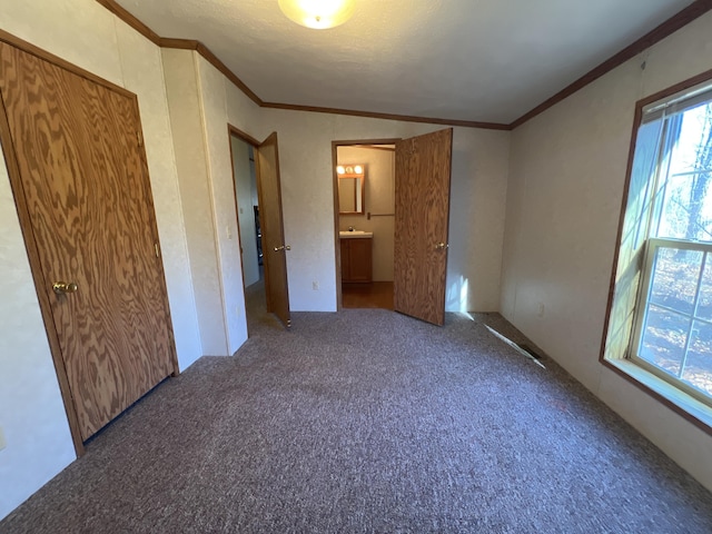 unfurnished bedroom with carpet flooring, ensuite bath, and crown molding