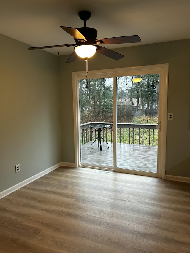 empty room featuring ceiling fan, baseboards, and wood finished floors