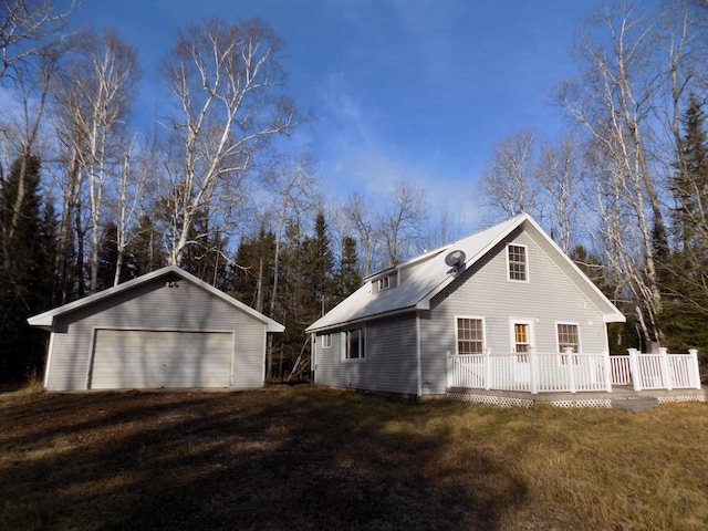 view of side of property featuring an outbuilding, a lawn, a garage, and a wooden deck