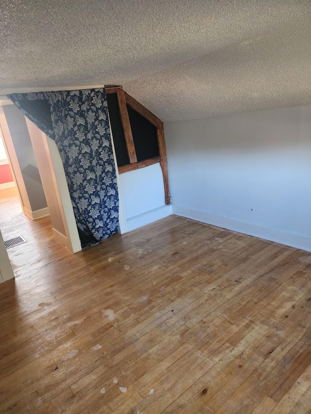 spare room featuring visible vents, a textured ceiling, and wood-type flooring