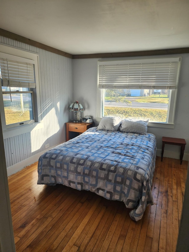 bedroom featuring multiple windows, baseboards, and hardwood / wood-style floors