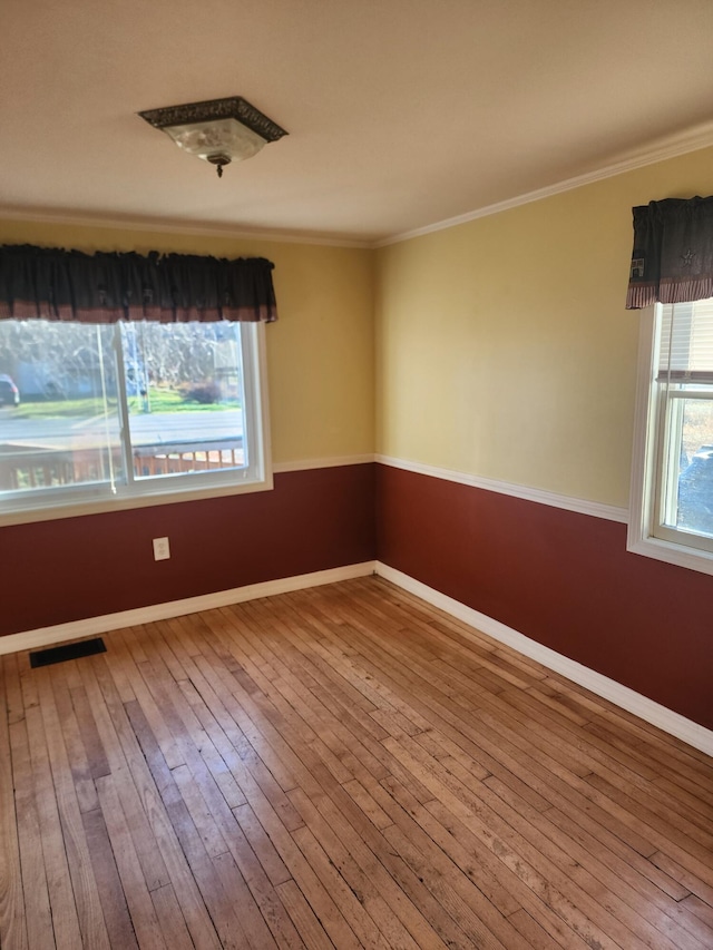 empty room featuring ornamental molding, baseboards, and hardwood / wood-style flooring