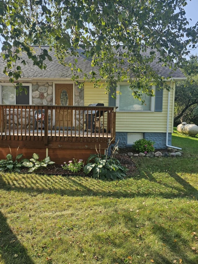 back of property featuring a lawn, a shingled roof, and a deck