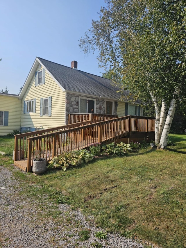 back of house featuring stone siding, a lawn, a deck, and a chimney