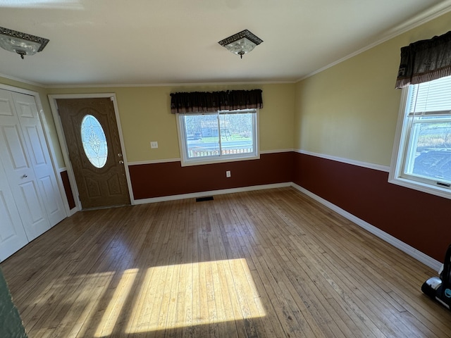 foyer entrance with a wealth of natural light, visible vents, ornamental molding, and hardwood / wood-style flooring