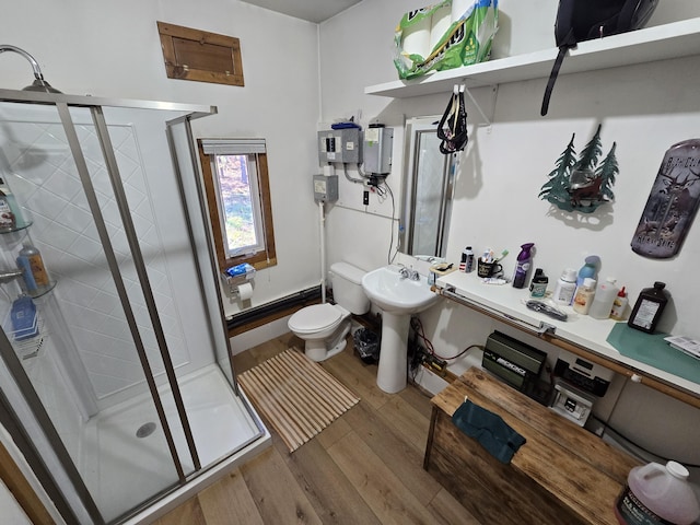 bathroom with toilet, water heater, a stall shower, wood finished floors, and a sink