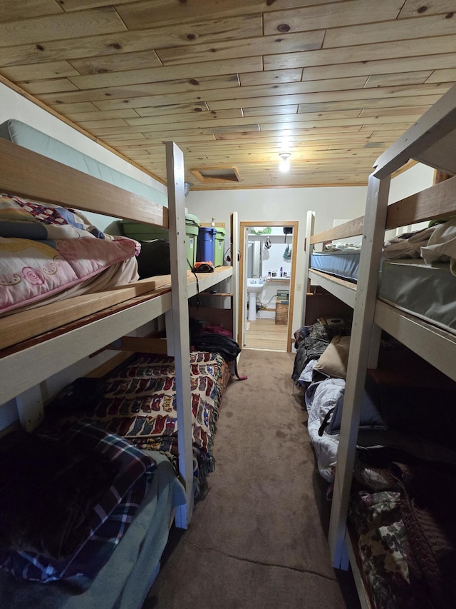 bedroom featuring ensuite bath, wooden ceiling, carpet, and a sink