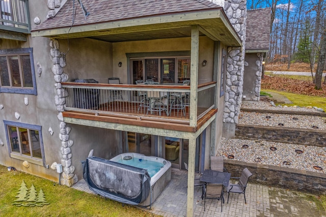 rear view of house featuring a patio, a hot tub, and a shingled roof