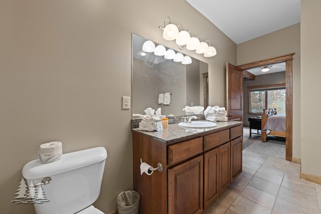 ensuite bathroom featuring tile patterned floors, toilet, ensuite bathroom, baseboards, and vanity