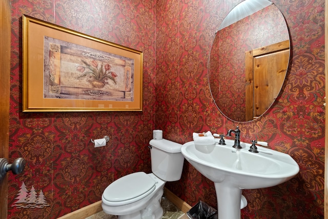 bathroom featuring baseboards, toilet, and wallpapered walls