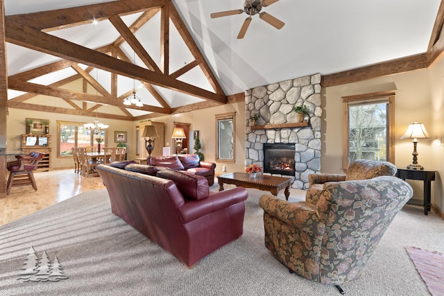 living area featuring a stone fireplace, ceiling fan with notable chandelier, a healthy amount of sunlight, and high vaulted ceiling