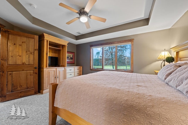 bedroom featuring a tray ceiling, ceiling fan, and carpet flooring