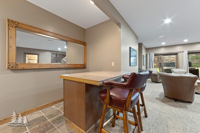 bar with recessed lighting, stone finish flooring, baseboards, and a bar