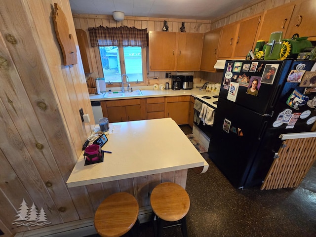 kitchen with wooden walls, freestanding refrigerator, range with electric cooktop, a sink, and light countertops