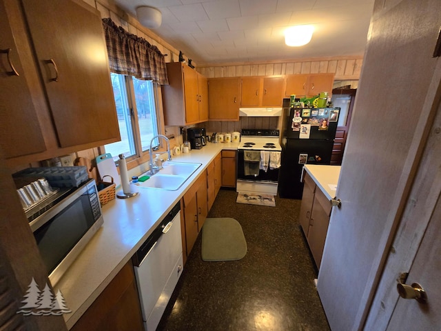 kitchen featuring under cabinet range hood, dishwasher, electric stove, freestanding refrigerator, and a sink