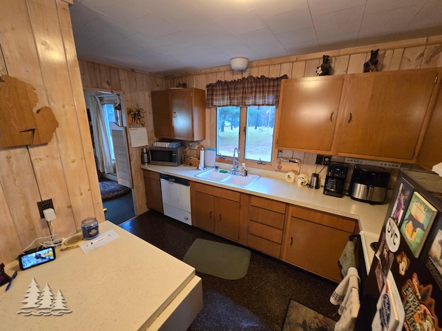 kitchen with white dishwasher, a sink, light countertops, wood walls, and stainless steel microwave