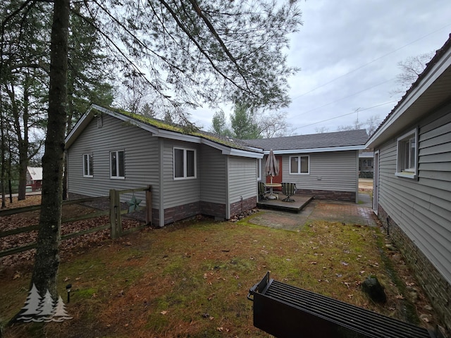 back of property with a wooden deck, a yard, and fence