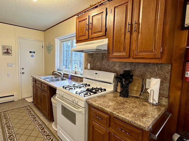 kitchen featuring white gas stove, under cabinet range hood, decorative backsplash, brown cabinetry, and a sink