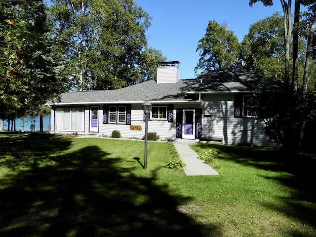 ranch-style house featuring a chimney and a front lawn