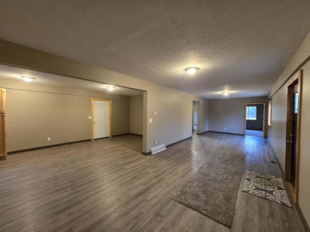 unfurnished room with visible vents, a textured ceiling, baseboards, and wood finished floors