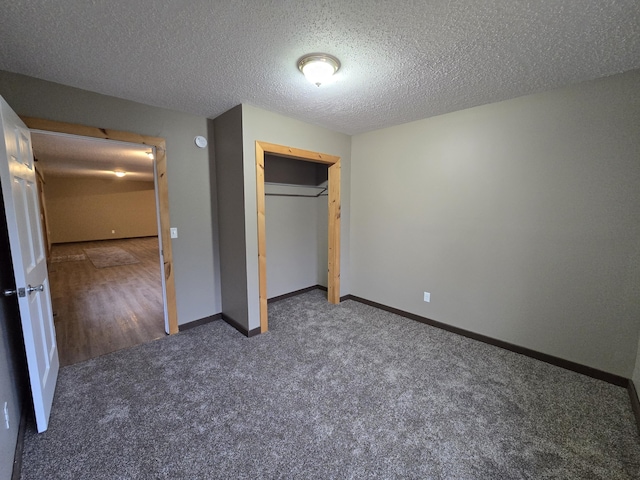 unfurnished bedroom with carpet flooring, baseboards, a closet, and a textured ceiling