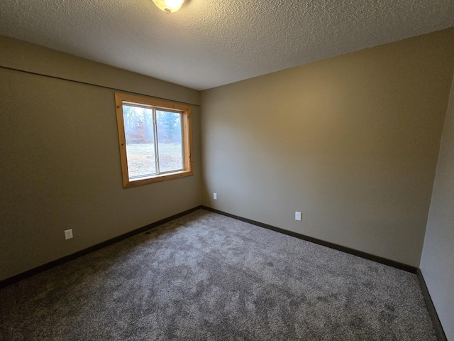 carpeted spare room featuring visible vents, a textured ceiling, and baseboards