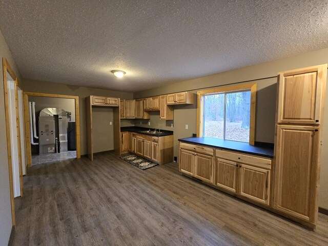 kitchen with dark countertops, arched walkways, dark wood-style floors, a textured ceiling, and a sink