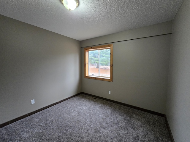 carpeted spare room featuring visible vents, baseboards, and a textured ceiling