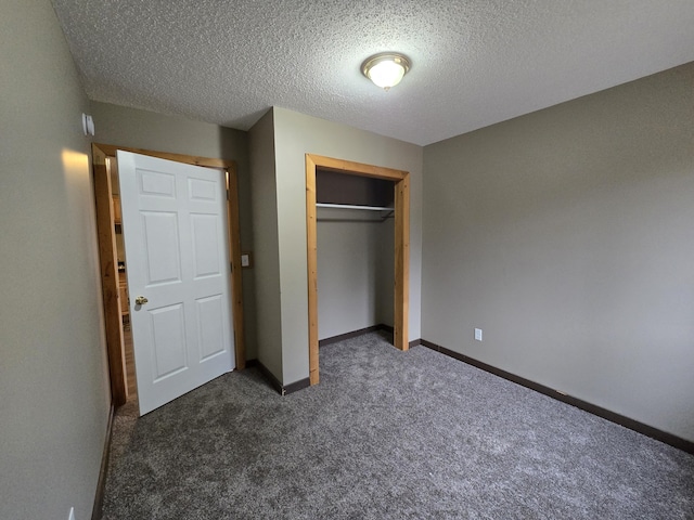 unfurnished bedroom with a closet, baseboards, dark carpet, and a textured ceiling