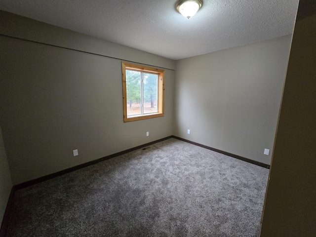 carpeted spare room featuring a textured ceiling and baseboards