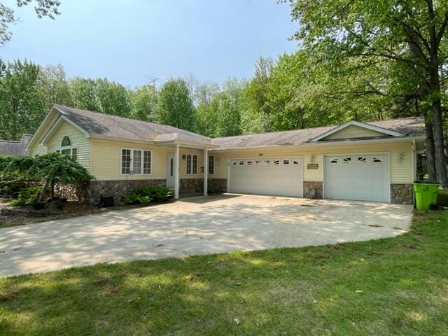 991 W Higgins Lake Dr, Roscommon, MI 48653 - ranch-style house featuring stone siding, an attached garage, concrete driveway, and a front lawn