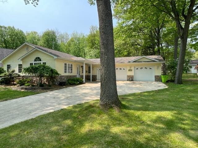991 W Higgins Lake Dr, Roscommon, MI 48653 - ranch-style house with concrete driveway, a garage, stone siding, and a front yard