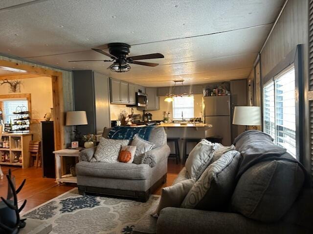 living room featuring ceiling fan, wood finished floors, and a textured ceiling