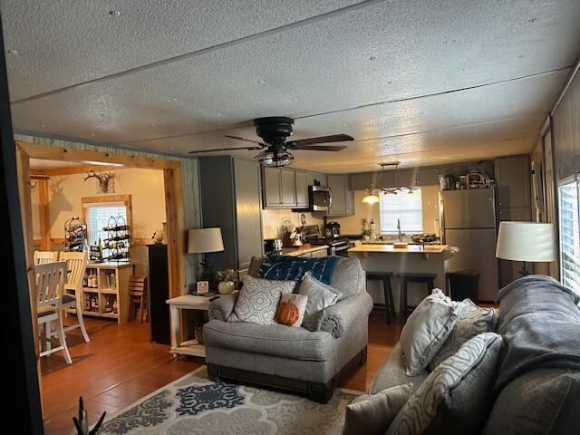 living area featuring a ceiling fan, wood finished floors, and a textured ceiling