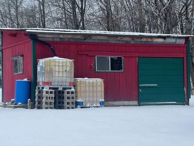 snow covered structure featuring an outbuilding