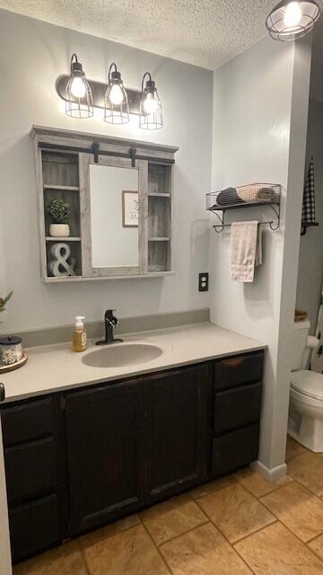 bathroom with vanity, tile patterned floors, toilet, and a textured ceiling