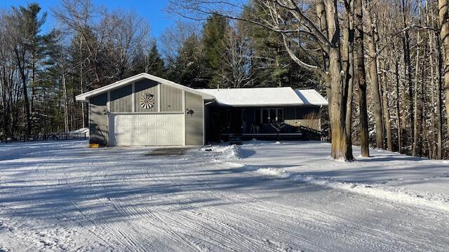 snow covered structure featuring a garage