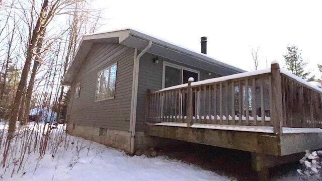 view of snowy exterior with crawl space and a wooden deck