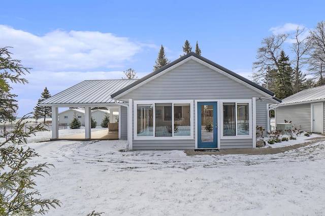 snow covered house featuring metal roof