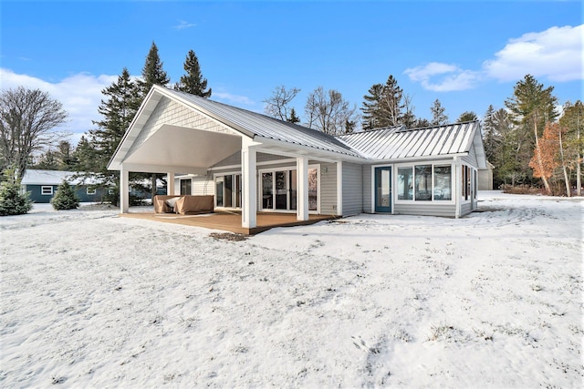 snow covered back of property featuring metal roof and a standing seam roof