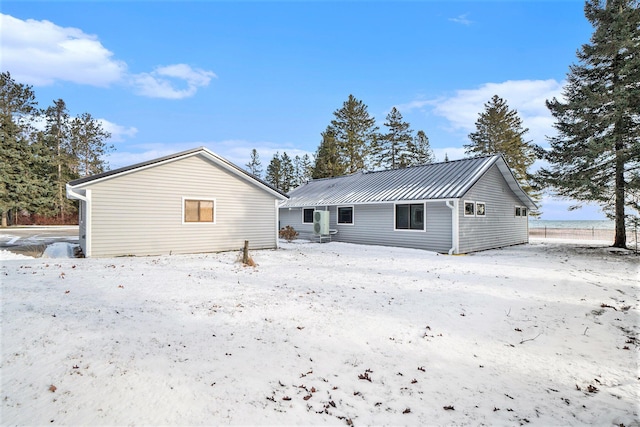 snow covered house featuring metal roof