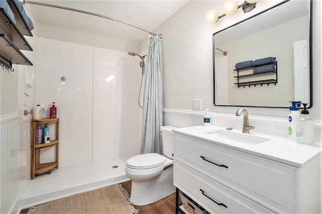 full bath featuring a wainscoted wall, toilet, wood finished floors, a shower with shower curtain, and vanity