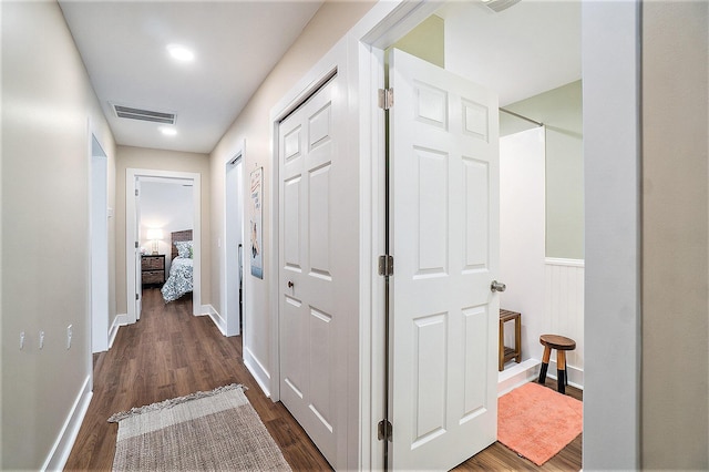 corridor with baseboards, visible vents, and dark wood-style flooring