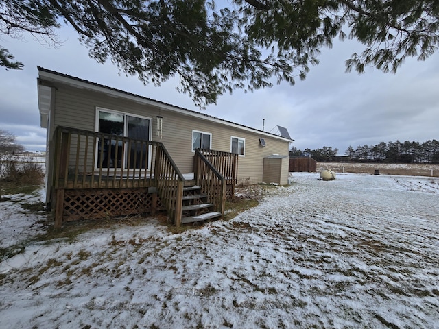 snow covered back of property featuring a wooden deck