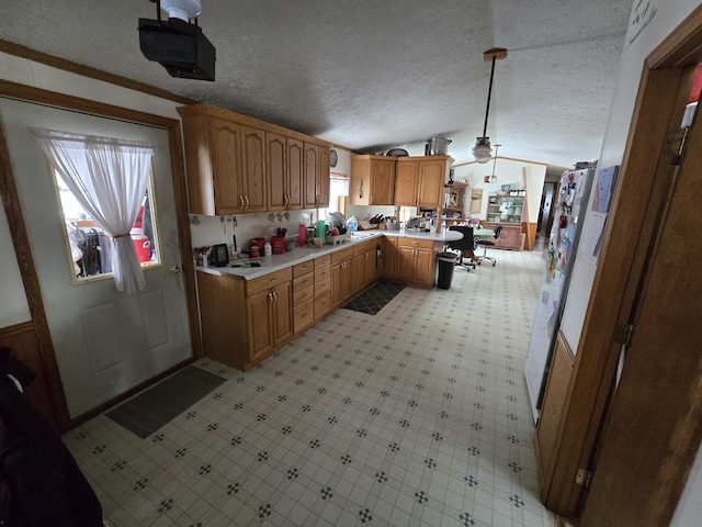 kitchen with a textured ceiling, a peninsula, light countertops, light floors, and vaulted ceiling