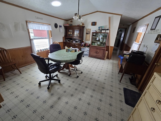 dining space with lofted ceiling, crown molding, a wainscoted wall, and wood walls