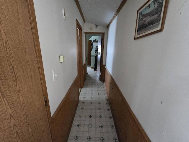 hall with lofted ceiling, light floors, and a textured ceiling