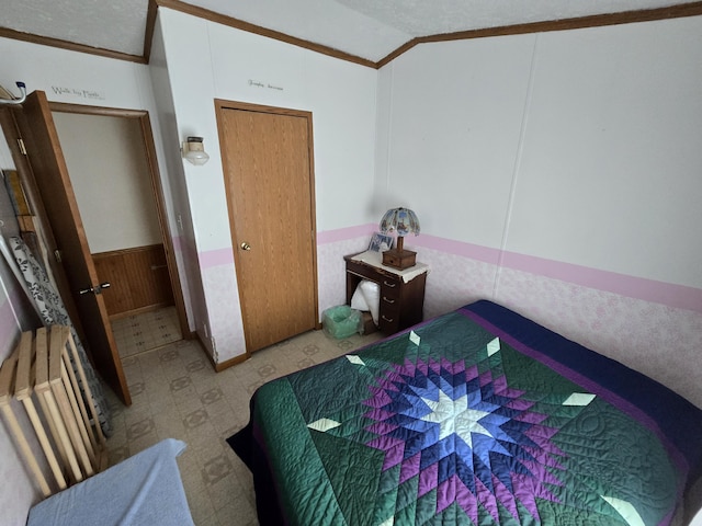 bedroom with wooden walls, lofted ceiling, ornamental molding, wainscoting, and tile patterned floors