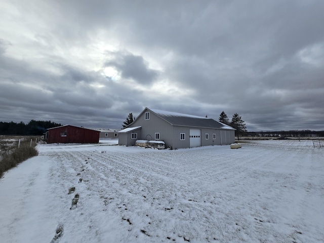 snow covered house featuring a garage and an outdoor structure